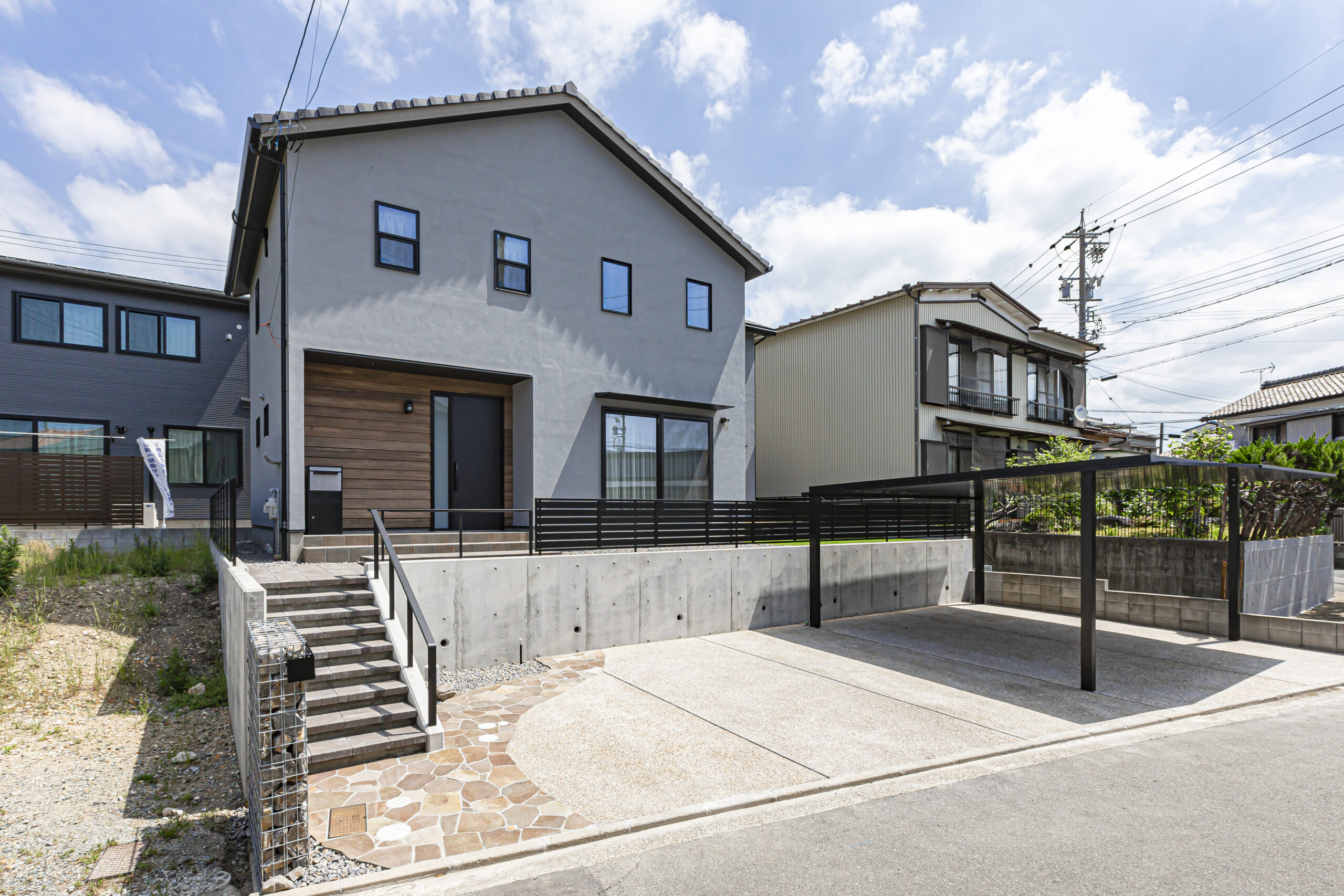 敷地内の高低差を活用した注文住宅の外観デザイン
洗い出しの駐車場と乱形の石張りがアクセントの外構工事