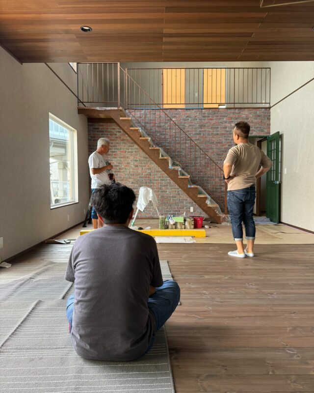 豊橋市の注文住宅施工現場で鉄骨階段のエイジング塗装を行う職人と見守るスタッフ