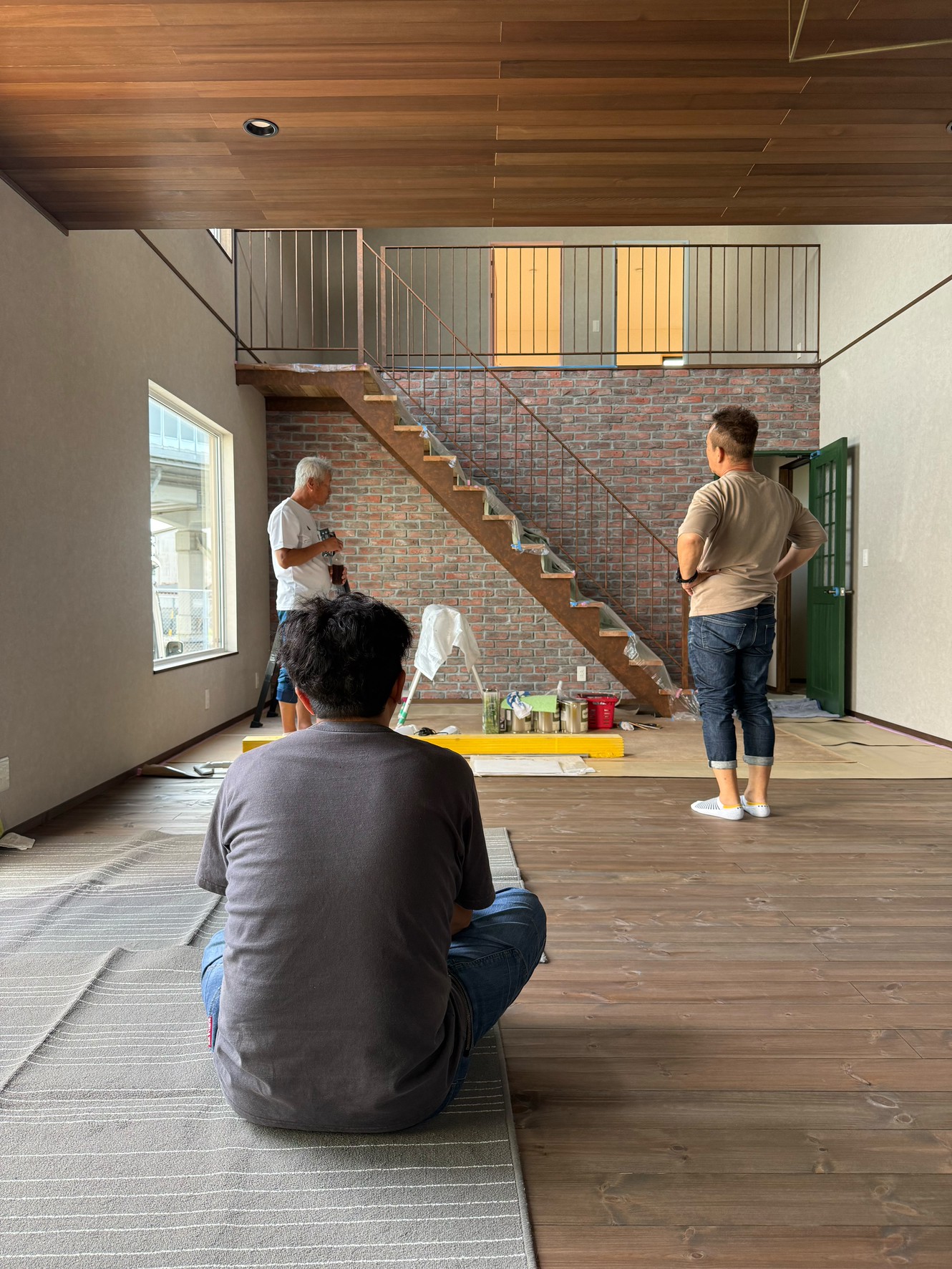 豊橋市の注文住宅施工現場で鉄骨階段のエイジング塗装を行う職人と見守るスタッフ